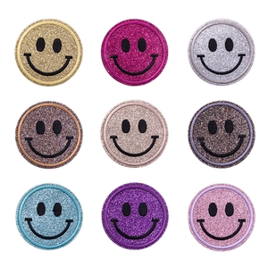 Close-up of nine colorful glitter sequin smiley face patches for DIY clothing decoration