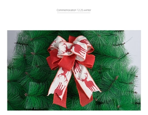 Detail of red and beige linen Christmas bow with elk pattern on green tree branches