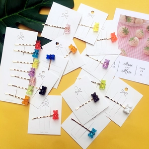 Close-up of colorful acrylic gummy bear hair clips on gold pins with a yellow background