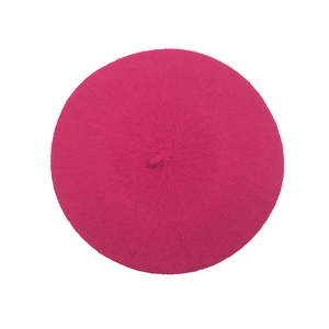 Top view of bright pink wool knit beret with a decorative stem on a clean white background