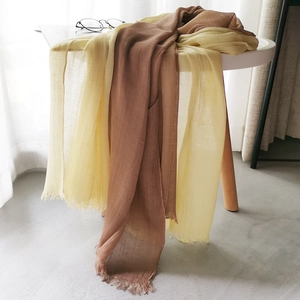 Detailed close-up of brown and pale yellow cotton linen scarves with fringe edges
