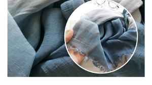 Detail of blue and gray gradient linen scarf showing woven texture and fringe trim