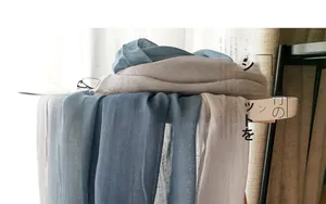 Detail of light gray and blue gradient linen scarf showing translucent fabric texture