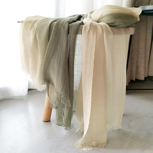 Detail of linen scarf with fringe edges in beige and olive green gradient tones