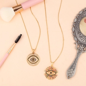 Golden Evil Eye necklaces with zircon inlay and sunburst design on pink background