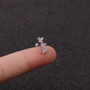 Nahaufnahme eines sternförmigen Ohrsteckers aus Stahl mit Zirkonia auf einer Fingerspitze