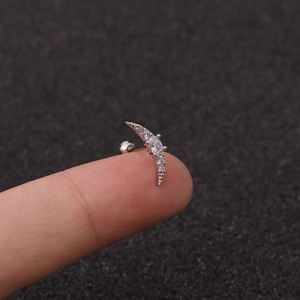 Detailed scale view of a silver moon-shaped stud earring with cubic zirconia on a finger