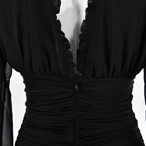 Detail of black deep V-neck dress featuring mesh fabric, ruffle trim and waist pleats