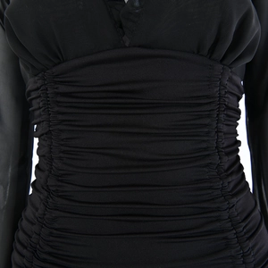 Detail of ruched waist design on a black bodycon dress with lace trim and mesh sleeves
