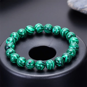 Detailed view of green natural malachite beaded bracelet with unique textures on black base