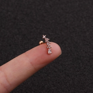 Macro detail of rose gold screw earring featuring zircon droplets held on a fingertip