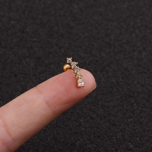 Close-up of curved gold ear piercing jewelry featuring sparkling drop-shaped zircon stones