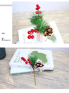 Detail of a Christmas branch with red berries, pine needles, and a snowy pinecone on a desk