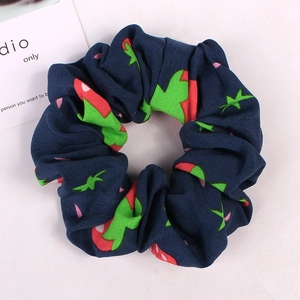 Close-up of a navy blue fabric scrunchie with cute red and green strawberry prints