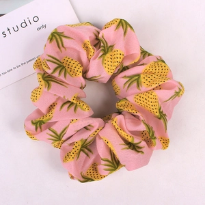 Detailed view of pink chiffon scrunchie featuring vibrant yellow pineapple patterns