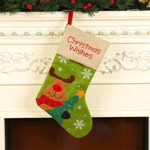 Green festive Christmas stocking with reindeer embroidery hanging on a classic fireplace