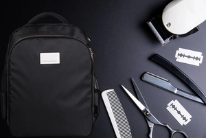 Flat lay of professional barber backpack with clippers, scissors and grooming tools