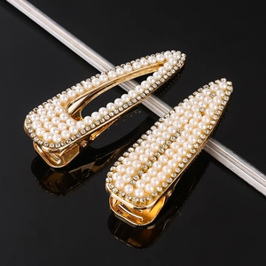Close-up of golden BB hair clips with white pearls and sparkling rhinestones