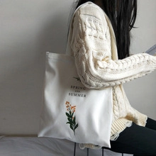 Modèle portant un sac cabas en toile blanche avec imprimé floral orange et texte d'été