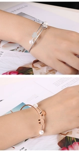 Detail of double-layer stainless steel wire bracelet with heart, clover and pearl charms