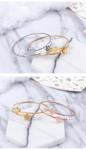 Macro view of woven steel bracelets with pearls and heart charms in gold and silver