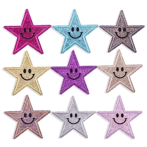 Detail of nine star-shaped sequin patches with black smiley embroidery in assorted colors