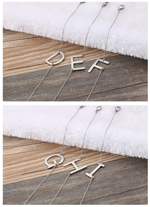 Dettaglio di collane in acciaio inossidabile argento con ciondoli lettere D, E, F, G, H e I