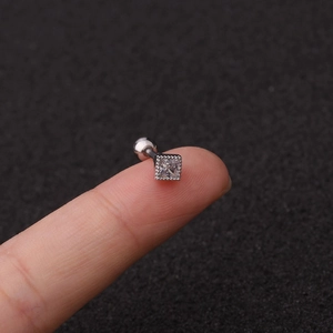 Square zircon screw back stud earring in stainless steel held on fingertip for scale