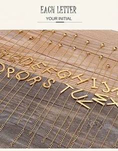Collection of gold stainless steel 26 alphabet letter bracelets on dark wood background