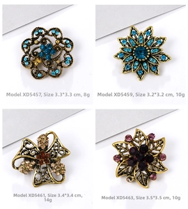 Detail of four vintage alloy brooches with rhinestones in floral and star patterns
