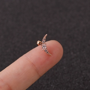 Macro shot of rose gold crescent moon stud earring with clear zirconias on fingertip