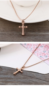 Close-up of rose gold cross pendant on a white ceramic edge with a minimalist metal chain