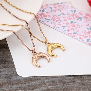 Gold and rose gold crescent moon horn necklaces with box chain on a white plate