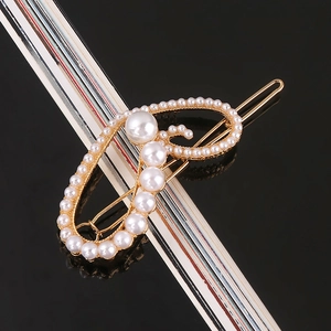 Detailed macro view of an elegant gold alloy hair clip with white faux pearls