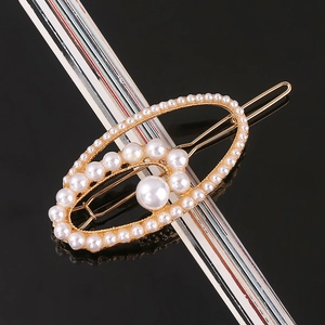 Close-up of elegant gold hollow hair clip with inlaid white pearls on black surface