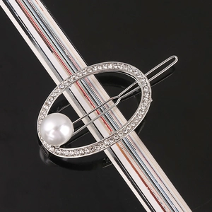 Detail of silver hair clip with oval rhinestone frame and a large white pearl accent