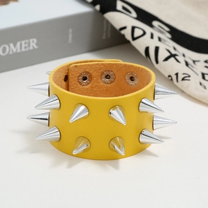 Close-up of punk yellow faux leather wristband featuring double-row silver metal cone studs