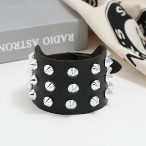 Macro detail of three-row silver cone studs on a black punk leather bracelet with buckle