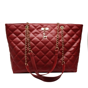 Red quilted tote bag with golden chain strap and deer charm on a white background