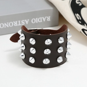 Macro detail of punk leather bracelet with three rows of silver cone studs and buckle