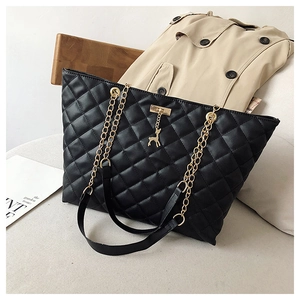 Detailed view of black quilted faux leather tote bag with gold chain and deer charm