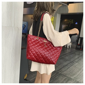 Detail of red quilted tote bag with golden deer pendant and metal chain strap