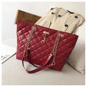 Detail of burgundy quilted tote bag featuring golden chain strap and deer pendant decoration