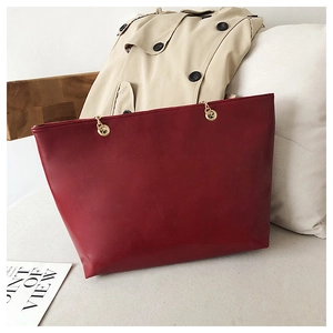 Detailed view of dark red tote bag with golden chain accents and matte leather texture