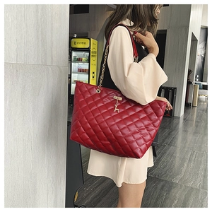 Close-up of red quilted shoulder bag with gold deer charm and elegant chain strap