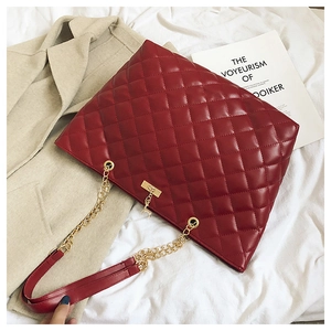 Macro shot of a red quilted shoulder bag featuring gold chain and diamond pattern
