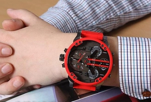 Close-up of oversize black multi-timezone watch with vibrant red silicone strap on wrist