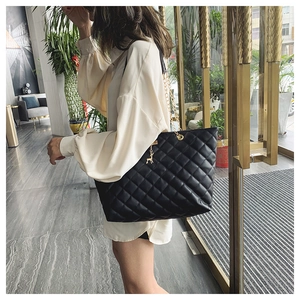 Quilted black shoulder bag with gold chain strap and deer charm on female model