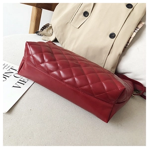 Detail of red quilted faux leather tote bag with elegant chain and spacious bottom design