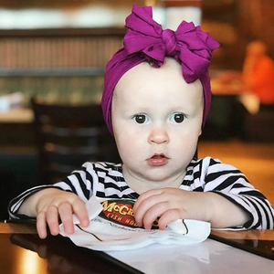 Bambino che indossa una morbida fascia in maglia viola con un grande fiocco elegante